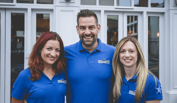 Three team members wearing a customised blue polo shirt