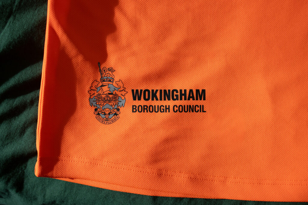 The bottom right hem of an orange hi-vis t-shirt featuring Wokingham Borough Council's logo.